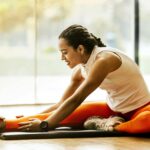 A woman enjoying a yoga stretch indoors, promoting a healthy lifestyle.